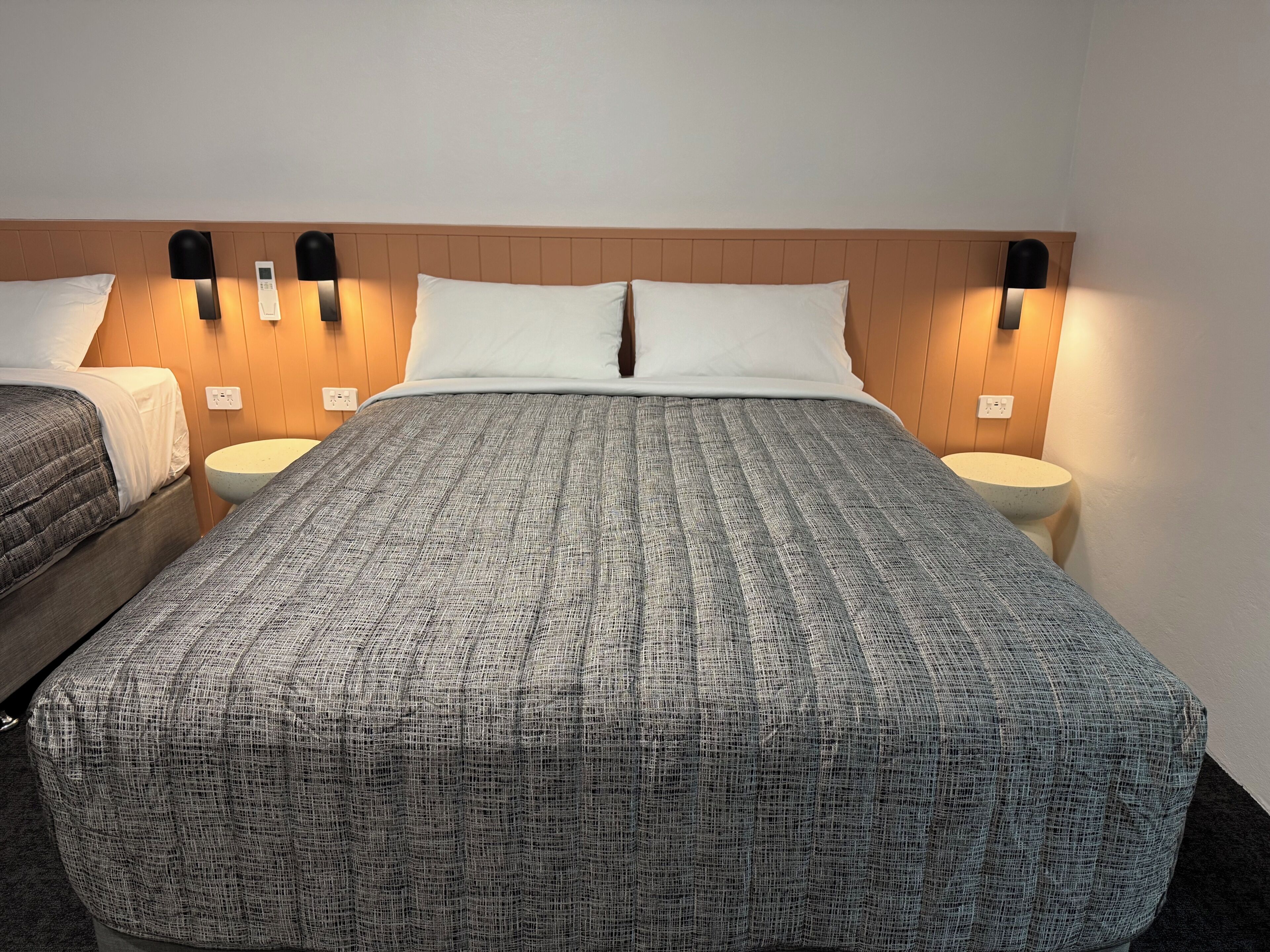 Ein Hotelzimmer mit einem großen Bett, zwei Nachttischen und Wandlampen.