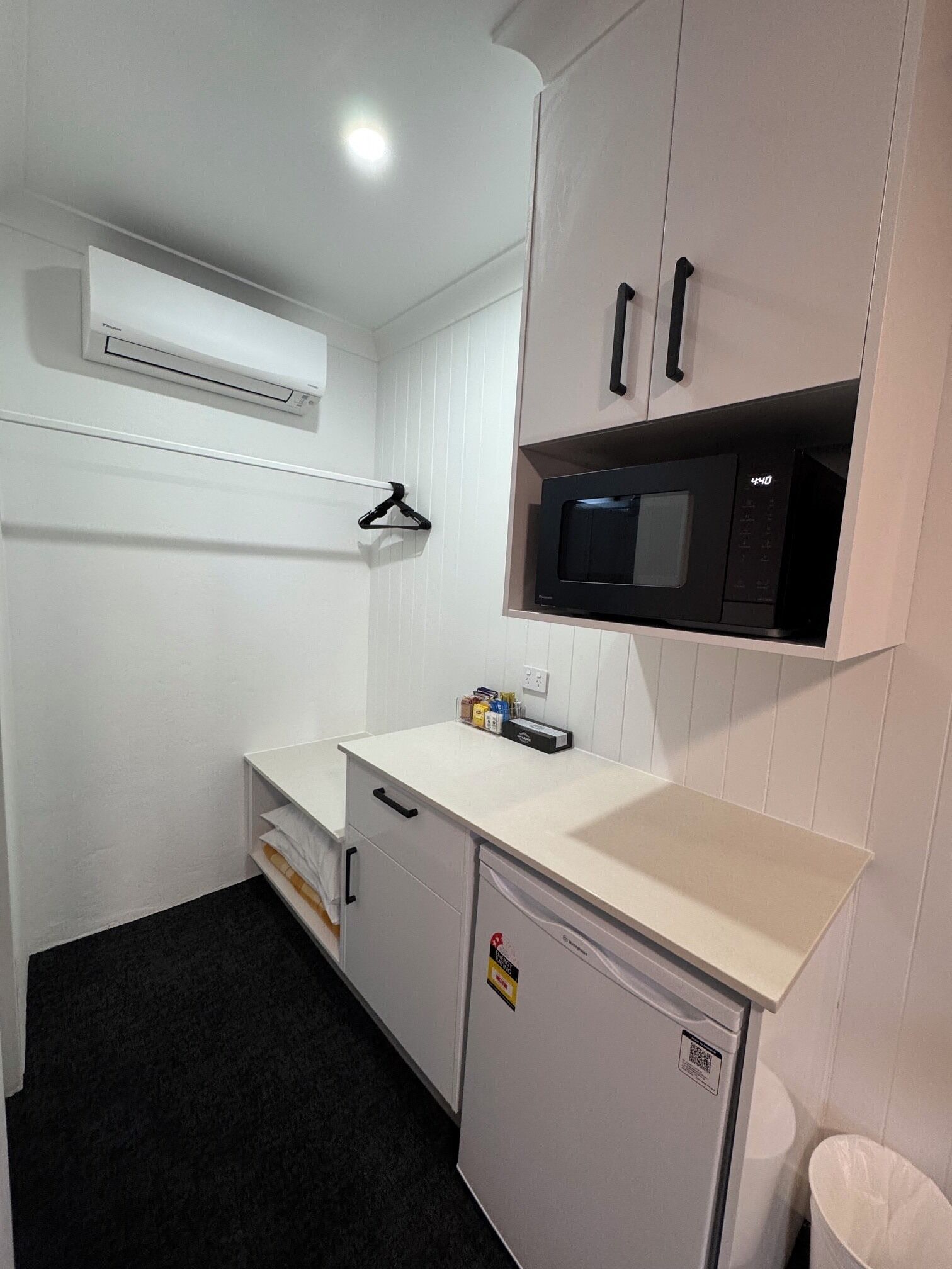 A compact kitchenette with a microwave, a small refrigerator, and a white countertop.