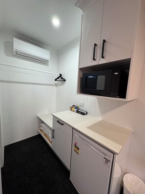 A compact kitchenette with a microwave, a small refrigerator, and a white countertop.