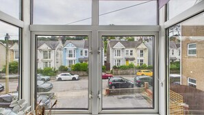 A bay window with a view of a row of houses and parked cars. - The Mews - 1 Bed Holiday Home - Langland (Swansea)