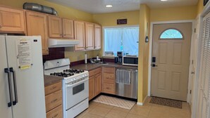 A compact kitchen with wooden cabinets, a gas stove, a refrigerator, a microwave, and a stainless steel dishwasher.