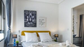 A hotel room with a bed, two bedside tables, a poster on the wall, and a door to the right. - Pink Harmony Apartment (Torrevieja)