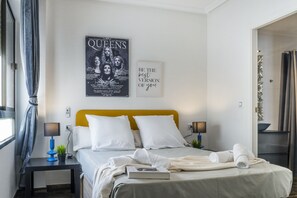 Ein Hotelzimmer mit einem Bett, zwei Nachttischen, einem Poster an der Wand und einer Tür rechts.