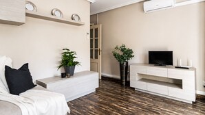 A modern living room with a sofa, a TV, a console table, and two potted plants. - Pink Harmony Apartment (Torrevieja)