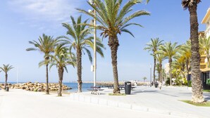 A coastal promenade with palm trees, a clear sky, and a view of the sea. - Pink Harmony Apartment (Torrevieja)