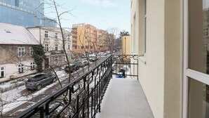 Un balcón con vista a una calle de la ciudad, edificios y una vía de tren.