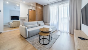 Een moderne woonkamer met een bank, een salontafel en een televisie.