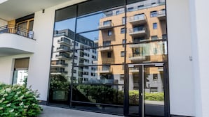 Een modern gebouw met grote raampartijen, een balkon en een reflectie van een ander gebouw.