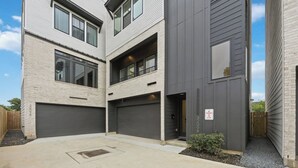 A multi-story residential building with two garages, a small garden area, and a 'NO PARKING ANYTIME' sign. - Wabi Sabi Studio in EADO (Houston)