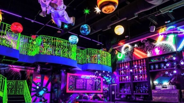 A vibrant bar area with neon lights, a bar counter, stools, and a neon sign. - Wabi Sabi Studio in EADO (Houston)