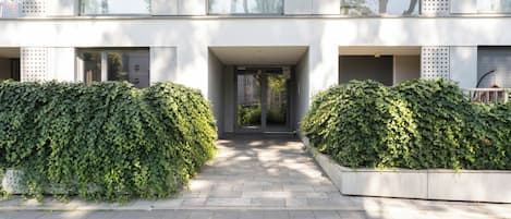 Un edificio moderno con entrada pavimentada, ventanas amplias y jardines simétricos.