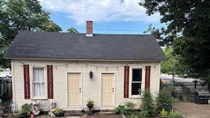 Une maison à deux étages, dotée d’une cheminée, d’un porche à l’avant et d’un petit jardin.
