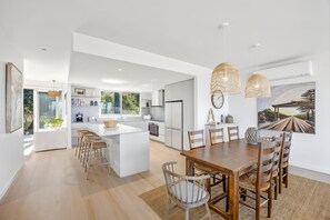 A modern kitchen with white cabinetry, a central island, and pendant lighting. - Stunning Roadknight Residence (Anglesea)