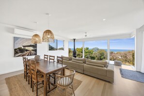 A modern living room with a dining area, large windows, and a view of the landscape. - Stunning Roadknight Residence (Anglesea)
