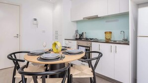 Una cocina moderna con armarios blancos, una mesa de comedor redonda con sillas y una pequeña isla con un objeto amarillo.