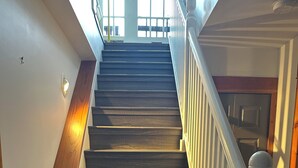Una escalera de madera con balaustres blancos que lleva a un rellano con una puerta.