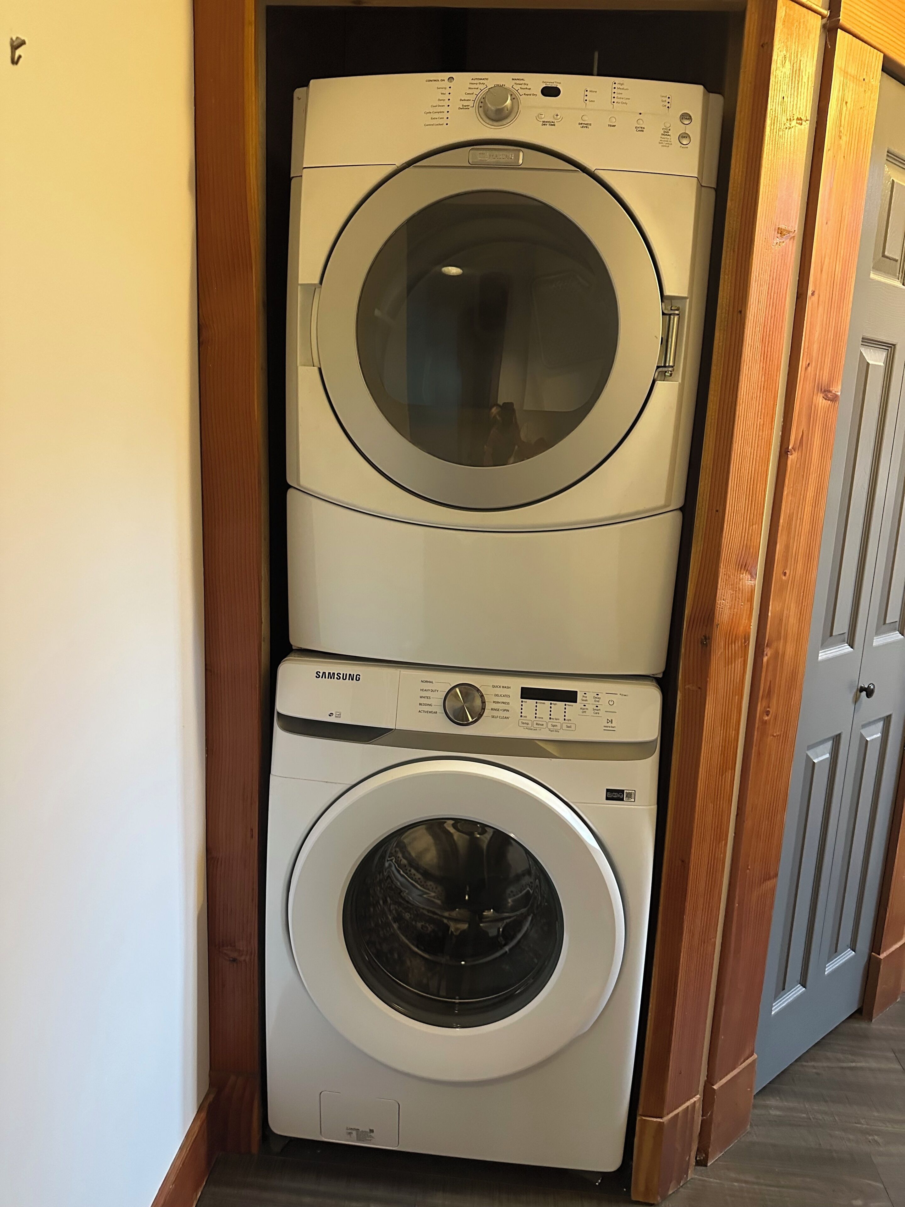 A stacked washer and dryer unit in a hallway.