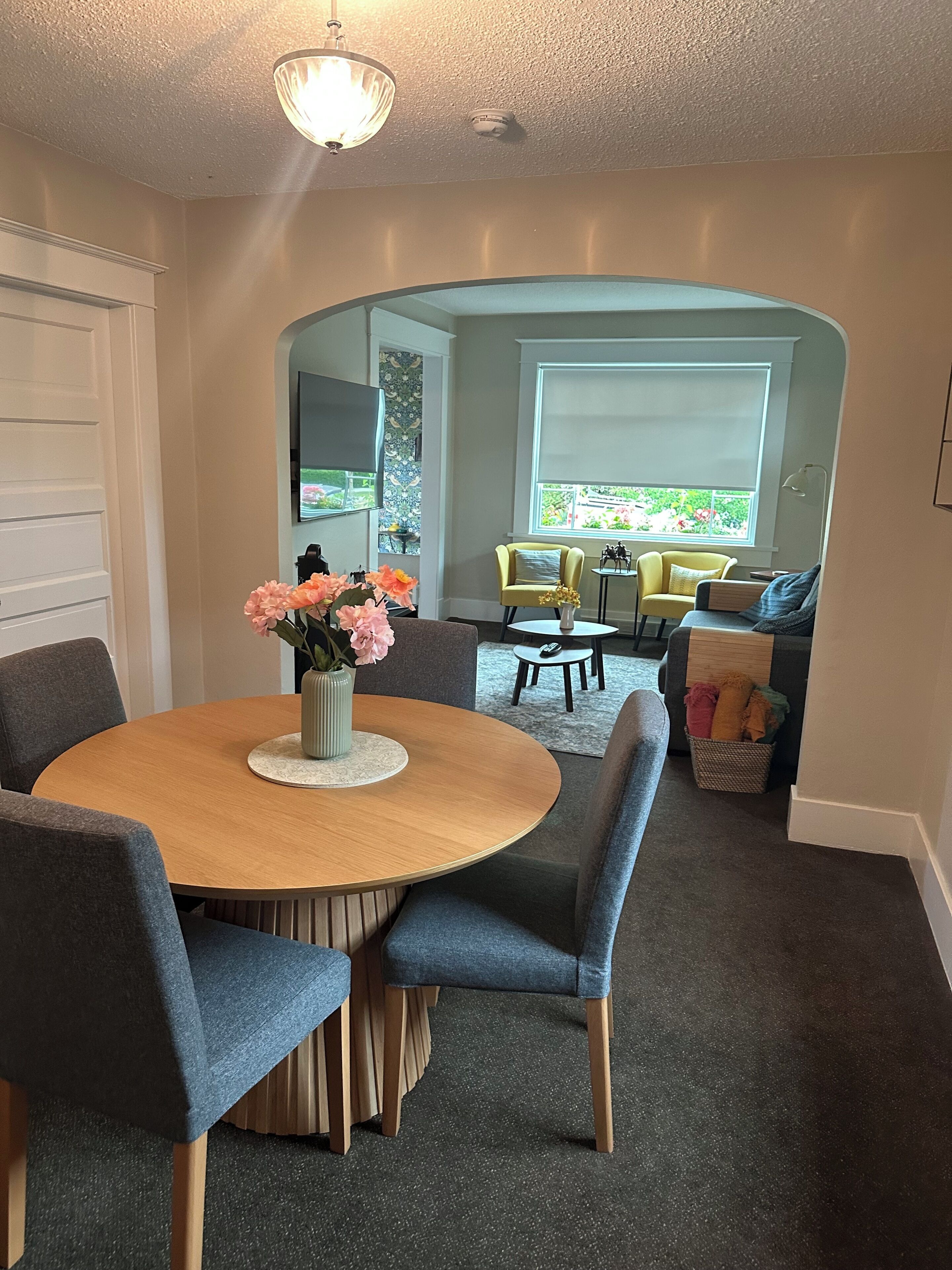 A dining area with a round table, chairs, and a vase of flowers.