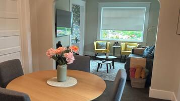 A dining area with a round table, chairs, and a vase of flowers.