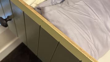 A wooden cabinet with a mattress and a folded blanket.