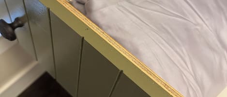 A wooden cabinet with a mattress and a folded blanket.