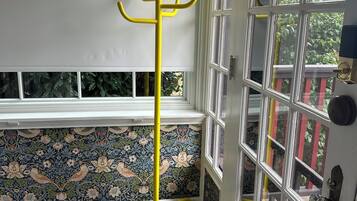 A room with a yellow coat rack, a patterned wallpaper, a wooden floor, and a door with multiple windows.