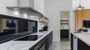 Een moderne keuken met een centraal kookeiland, een inbouwoven en een roestvrijstalen afzuigkap.