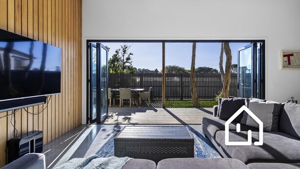 Een moderne woonkamer met een flatscreen televisie, een bank en een eethoek met stoelen.