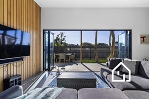 Una sala de estar moderna con un televisor de pantalla plana, un sofá y un comedor con sillas.