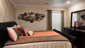 A bedroom with a bed, a dresser, a mirror, and a wall decoration.