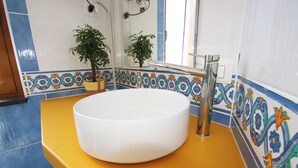 Une salle de bain avec un lavabo blanc, un plan de toilette jaune et des carreaux décoratifs.