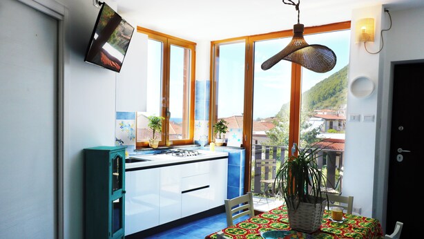 Une cuisine avec une fenêtre, une table à manger recouverte d’une nappe et une chaise.