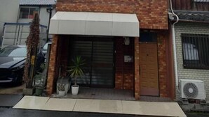 Un edificio de dos pisos con techo plano, fachada de ladrillo y una entrada central con puerta corredera.