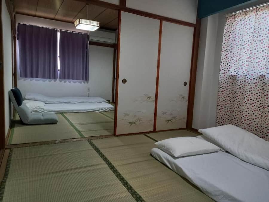 Une pièce de style japonais traditionnel, avec un sol recouvert de tatamis, un futon servant de lit, un paravent shoji et une porte coulissante.