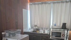 Cocina compacta con refrigerador, microondas y lavamanos.