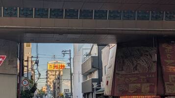 A street with a pedestrian crossing under an overpass. There are bicycles parked on the side, and a few cars on the road.
