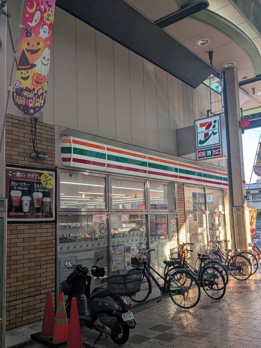 Una tienda de conveniencia 7-Eleven con una zona de aparcamiento para bicicletas y un patinete estacionado afuera.