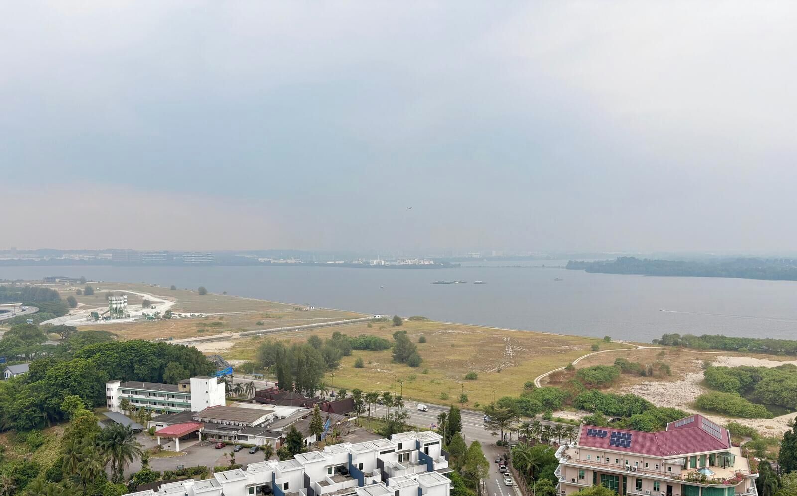 A coastal view with buildings, a road, and a body of water.