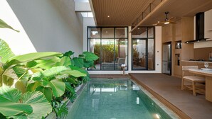 Eine moderne Küche mit eingebautem Herd, ein Essbereich mit Tisch und Stühlen sowie ein großes Fenster mit Blick auf einen Pool.
