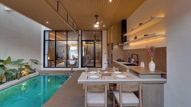 Eine moderne Küche mit Essbereich, einem Pool und Blick zum Wohnbereich.