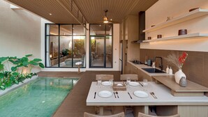 Eine moderne Küche mit Essbereich, einem Pool und Blick zum Wohnbereich.