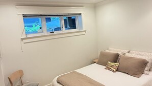 Een slaapkamer met een bed, een stoel, een raam en een plafondlamp.