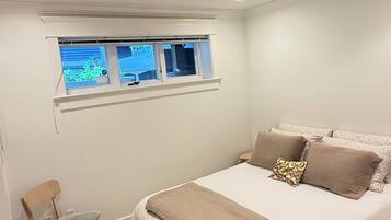 A bedroom with a bed, a chair, a window, and a ceiling light.