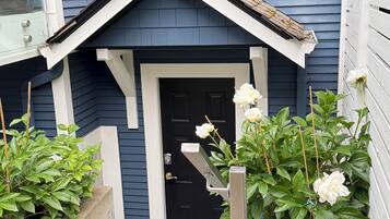 A house with a black door, a small porch, and a concrete pathway leading to the entrance.