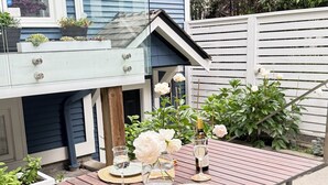 Een houten tuintafel met een bankje, omringd door bloempotten en bloemen.
