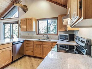 A kitchen with wooden cabinets, a stainless steel dishwasher, a microwave, and a stove.