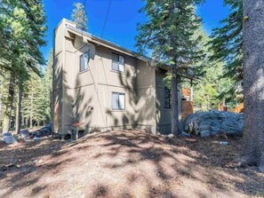 Un bâtiment à deux étages, doté d’un toit en pente et entouré d’arbres.