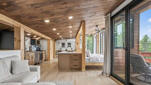 A modern interior with a wooden ceiling, a kitchen, a dining area, and a large sliding glass door to an outdoor deck. - Scandinavian-Modern Couples Retreat w/ Sauna, Hot Tub & Cold Plunge (Stow)