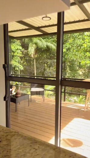 A room with large windows, a wooden deck, and a view of greenery outside. - Rio Celeste, Costa Rica, 2-bedroom apartment with AC (Provincia de Alajuela)