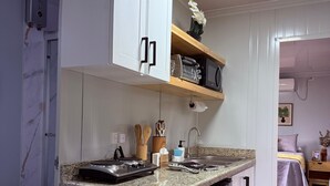 A compact kitchen with white cabinets, a granite countertop, and a built-in dishwasher.